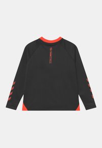 Svart långärmad skjorta med orange accenter vid kragen och sidorna, med randiga detaljer på ärmarna och en texturerad tyg.