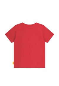 Red cotton t-shirt with a round neckline and short sleeves. Features a small yellow tag on the lower left side. Smooth texture and solid design.
