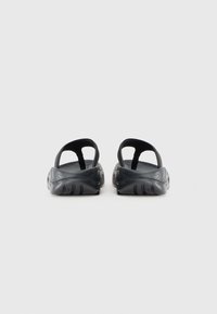 Sandales noires avec des semelles texturées et un design ouvert à l'arrière. Fabriquées en matériau flexible avec des brides minimales pour un maintien sécurisé.