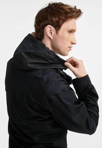 Czarna kurtka o miękkiej, gładkiej fakturze. Posiada kaptur, zamek błyskawiczny oraz dopasowany krój. Skupiona na modelu poprawiającym kołnierz.