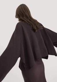 Dunkelvioletter, übergroßer Pullover mit weiten Ärmeln und einem cropped Design. Weicher Stoff mit einem schlichten, nahtlosen Abschluss am Saum.