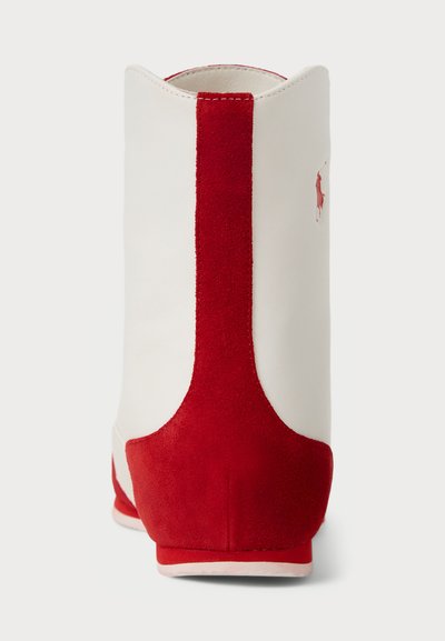 Weißer Stiefel mit einem roten Wildleder-Rücken und Akzenten, runder Spitze und glatter Textur. Kleines Logo an der Seite. Flache Sohle.