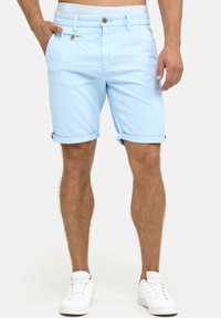 Lyseblå bomulds shorts med op rullede kanter, to sidelommer og knaplukning. Bæres med hvide sneakers.