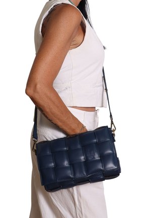 Borsa a spalla in pelle intrecciata blu navy con tracolla removibile, forma rettangolare, texture liscia, con dettagli a griglia e hardware dorato.