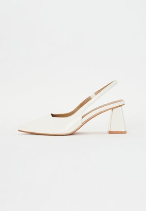 Weißer Slingback-Schuh aus Lackleder mit spitzer Schuhspitze und einem klobigen, ausgestellten mittelhohen Absatz vor weißem Hintergrund.