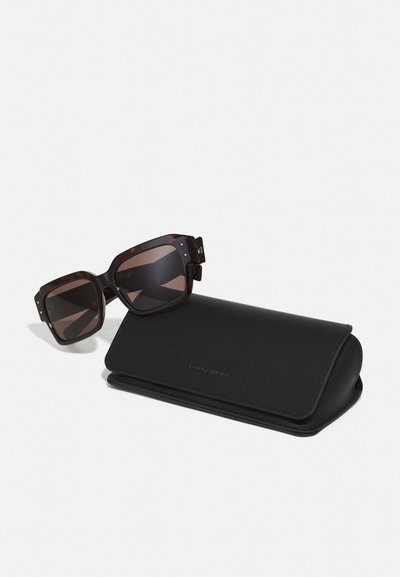 Ochelari de soare cu gel cu țestoasă brown și lentile închise, alături de o carcasă din piele neagră, cu o textură netedă și hardware minim.