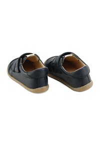 Zapatos de cuero negro con perfil bajo, que cuentan con cierres de correa ajustables y suela de goma texturizada. Interior forrado con material suave.