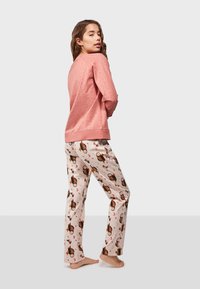 Pink long-sleeve top with perforated design and matching pajama pants featuring a whimsical owl and moon pattern on a light background.