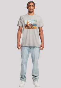 Grey cotton t-shirt featuring a colorful vintage print of a person on a motorcycle by the beach, with contrasting accents and a relaxed fit.
