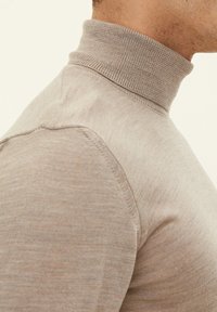 Beige Rollkragensweater mit tailliertem Design. Mit geripptem Kragen, glatter Textur und Nahtdetails an Schultern und Seiten.