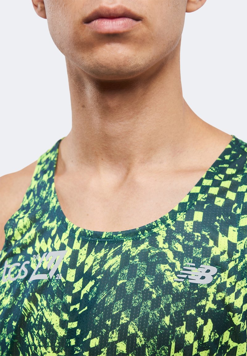 Gros plan d’une personne portant un débardeur de sport à motifs vert néon et noir avec des logos sur la poitrine.