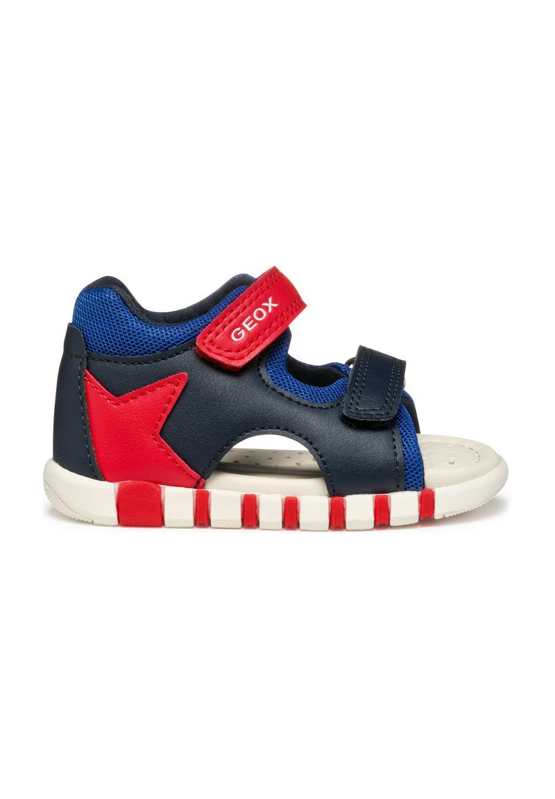 Sandal blu e navy con accento a stella rossa, cinturino regolabile e lati in rete traspirante. Suola testurizzata con strisce bianche e rosse.