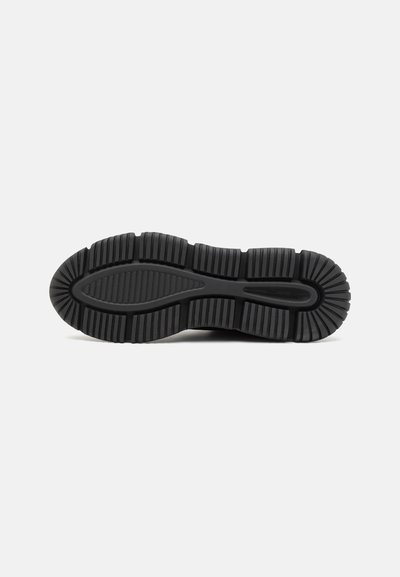 Black rubber shoe sole with deep grooves for traction, rounded toe, and a textured surface for grip. No visible branding or logos.