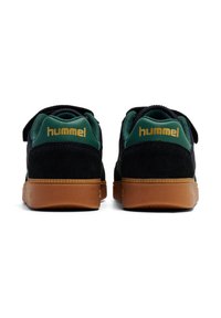 Sneakers neri in suede con accenti verdi, dotati di una fascia in Velcro e suola in gomma naturale. Logo "Hummel" in oro sul retro.