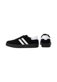 Czarne zamszowe sneakersy z białymi akcentami i trzema białymi paskami po boku, charakteryzujące się niskoprofilowym designem i teksturowaną podeszwą.