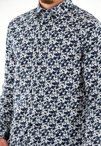 Wit en marineblauw shirt met lange mouwen, voorzien van een bloemenpatroon, een button-down kraag en zwarte knopen aan de voorkant.