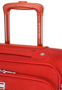Roter Hartschalenkoffer mit strukturierten Oberflächen, ausziehbarem Griff und Reißverschlussdetails; Markenlogo auf dem Griff sichtbar.