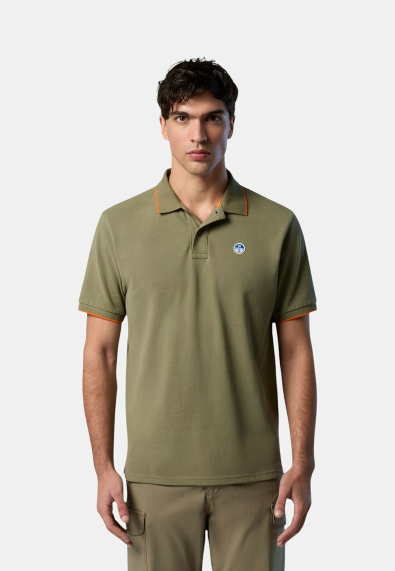 Polo verde oliva con piping arancione sul colletto e sulle maniche, caratterizzato da un logo rotondo sul petto. Tessuto morbido in misto cotone.
