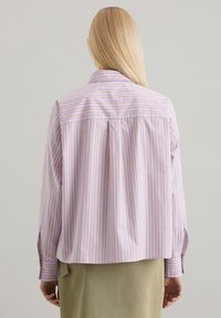 Paarse en witte gestreepte shirt met lange mouwen, voorzien van subtiele gele accenten, een achterpand en een ontspannen pasvorm.