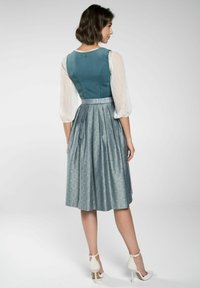 Teal lijfje met een gestructureerde witte mouw, aangevuld met een geplisseerde zilveren rok. Heeft een strakke taille en een geaccentueerde achterkant.