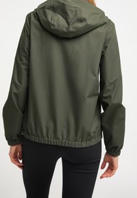 Oliwkowa kurtka z kapturem i elastyczną talią, wykonana z gładkiego, lekkiego materiału i z długimi rękawami.