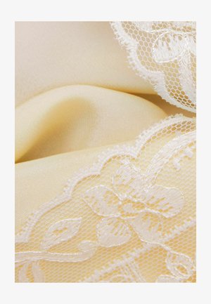 Crème satijnen stof met delicate witte kant met bloem- en bladmotieven langs de randen.