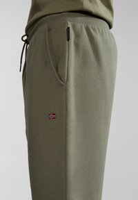 Olivově zelené tepláky z měkké látky, s šňůrkovým pasem, boční kapsou a malou vlajkou Norska jako emblémem.