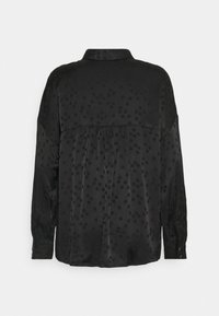 Black satin blouse with polka dot pattern, long sleeves, and a collar. Features a pleated back and button details on cuffs.