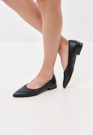 Ballerine in pelle nera con punta appuntita, tacco basso e una consistenza complessivamente liscia; presenta un design ritagliato lungo i lati.