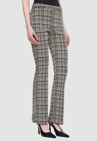 Pantaloni a quadri su misura in grigio e nero con design a gamba svasata. Presentano una texture liscia e tasche anteriori nascoste.