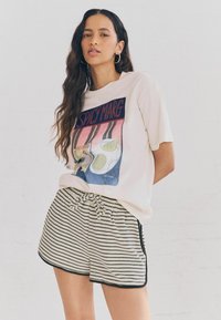 Vit t-shirt med en färgglad grafisk tryck av limecocktails, i kombination med svartvita randiga shorts med dragsko i midjan.