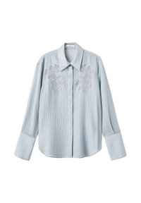 Camisa de color azul claro hecha de una tela texturizada con cuello puntiagudo. Presenta bordados florales blancos en el pecho y mangas largas con puños.