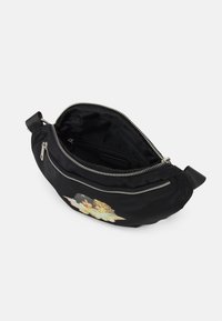 Svart nylon midjeväska med sneddraget blixtlås, prydd med en ängelgrafik. Insidan är fodrad, med ett enda ficka med blixtlås och justerbar rem.