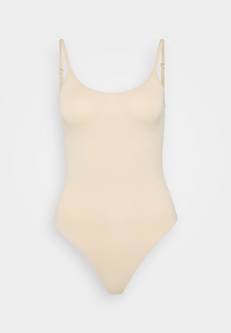 Beige bodysuit med tunna justerbara axelband, slät textur, rundad halsringning och en tanga-botten designad för en sömlös passform.