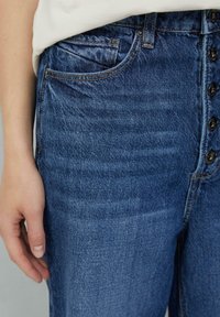 Hoge taille spijkerbroek in donkerblauw met een gladde textuur, met een knoopsluiting en voorzakken. Accentueert de contrasterende stiksels.