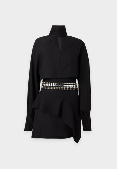 Tenue noire à manches longues avec col montant boutonné, crop top, ceinture cloutée et jupe asymétrique à volants, présentée sur un fond clair.