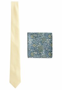 Gul slips med et struktureret mønster ved siden af en mørkeblå lommetørklæde med et blomstermotiv i hvide og gule nuancer.