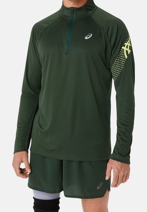 Haut athlétique léger et vert avec des manches longues, un zip jusqu'à mi-hauteur à l'avant et un motif texturé ; présente un logo et un design d'accent en jaune sur la manche.