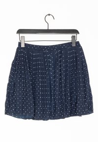 Marinblå veckad kjol med vita stjärnprickar, lätt tyg, smal midja och en svävande design, hängande på en svart plastgalge.