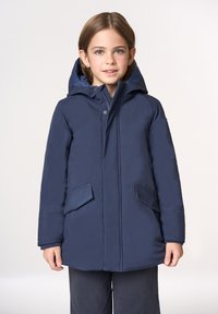 Cappotto imbottito blu scuro con cappuccio, dotato di una cerniera frontale e due grandi tasche applicate. Tessuto liscio con cuciture minimaliste.