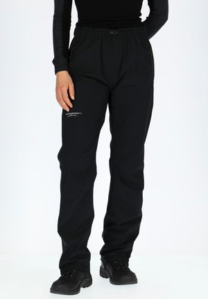 Black waterproof pants with elastic waistband, zippered pockets, and elastic cuffs. Features logo detail on the left leg.