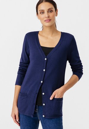 Marine blauwe cardigan met een V-hals, knopen aan de voorkant, lange mouwen en twee voorzakken. Gemaakt van zachte stof. Eenvoudig ontwerp met geribde accenten.
