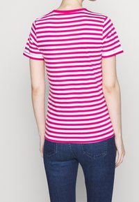 Camiseta ajustada con rayas horizontales rosas y blancas, cuello redondo, mangas cortas y tela de algodón suave, combinada con jeans azul oscuro.
