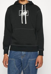 Black hoodie made of soft fabric, featuring a white logo in a rectangular frame, adjustable drawstring, and front kangaroo pocket.
