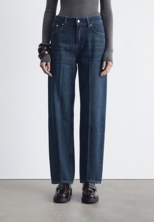 Dark blue high-waisted jeans made of denim, featuring wide legs, subtle fading, and classic five-pocket design. Worn with dark shoes.