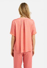 Rosa Schlafanzug-Set mit einem geometrischen Wabenmuster und gelben Akzenten. Kurze Ärmel, lockere Passform und glatte Textur. Rückansicht.