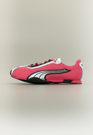Chaussure de sport rose profil bas avec des bandes latérales noires et blanches, tige en maille, semelle noire et lacets roses et noirs, vue de côté.