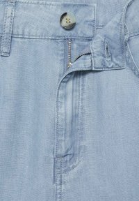 Pantalon en denim bleu clair avec une fermeture éclair, un zip argenté et un bouton rond unique à la taille, avec des coutures pour les poches latérales.