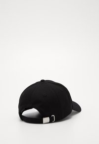 Casquette de baseball noire en coton, avec un visière courbée, une sangle réglable avec une boucle en métal et des détails de couture.