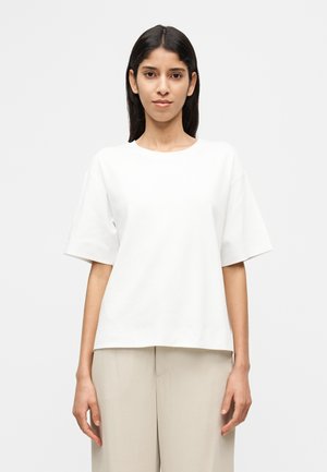 White short-sleeve t-shirt with a crew neck, made of a soft fabric, relaxed fit, and straight hem, paired with light beige trousers.